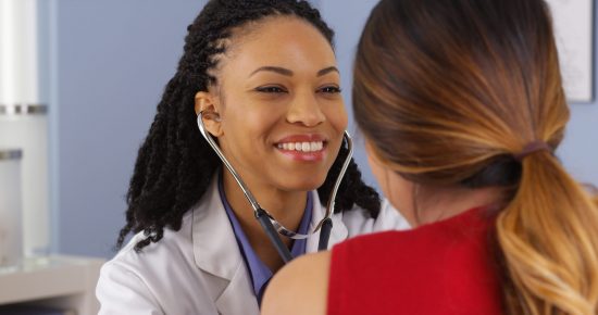 Close up of African American physician listening to heart and lungs of patient
